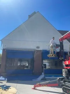 Commercial building gable painting with boom lift