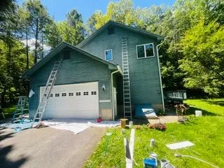 Green house garage exterior painting with ladders