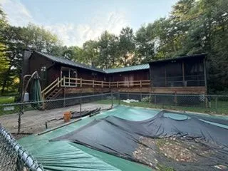 Stained wood house and deck beside covered pool